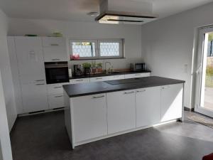 cocina con armarios blancos y encimera negra en Nice Room with single bed in a new house in Vichten, en Vichten