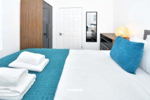 een slaapkamer met een wit bed met blauwe kussens bij Gilman House by Truestays - 4 Bedroom House in Stoke-on-Trent in Etruria
