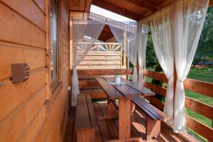 a wooden porch with a wooden table in a cabin at Domki Rejs in Dębki