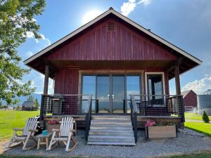 a red barn with two chairs and a porch at New Cabin with Spectacular Views of Flathead Lake. in Somers