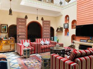 Traditional house (Riad) in the heart of Rabat medina في الرباط: غرفة معيشة مع كنب وتلفزيون بشاشة مسطحة