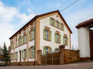 a building with green windows and a fence at Klosterhof Weingut BoudierKoeller in Stetten