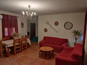 een woonkamer met een rode bank en een tafel bij Casa rural Los Alcaidejos con piscina in Málaga
