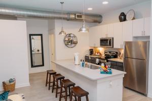 a kitchen with a counter and a refrigerator and chairs at Downtown/Midtown Loft-Pool-Free Parking in Houston