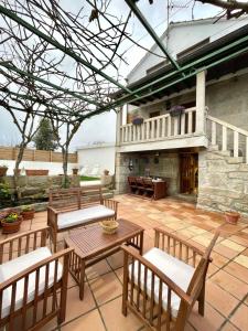 a patio with benches and a table and a building at La Casita in Nogueira de Ramuin