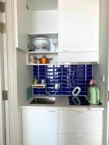 una cucina con armadi bianchi, lavandino e piastrelle blu di P.H.O Apartment a Phu Quoc