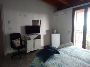 1 dormitorio con 1 cama, TV y silla en No Zu Filì, en Villaggio Mosè