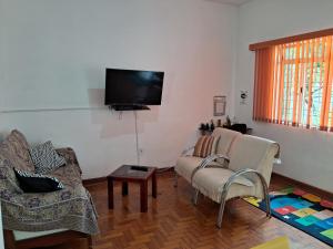 - un salon avec deux chaises et une télévision à écran plat dans l'établissement Casa Térrea SP Expo e C Paralimpico, à São Paulo