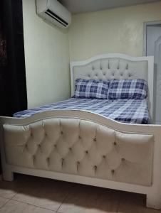 uma cama branca com um cobertor xadrez azul e branco em El anexos em Santiago de los Caballeros