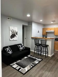ein Wohnzimmer mit einem schwarzen Sofa und einer Küche in der Unterkunft Warm and Cozy Retreat in Morgantown