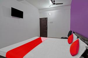 OYO Flagship Hotel Sun City في باتنا: غرفة نوم مع سرير وتلفزيون على الحائط