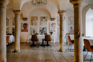a dining room with tables and portraits on the walls at Klosterhof Weingut BoudierKoeller in Stetten