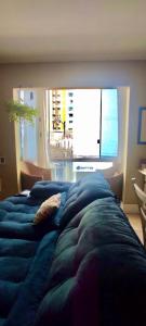 um quarto com uma cama azul e uma grande janela em Apartamento com localização fantástica na praia de Balneário Camboriú em Balneário Camboriú