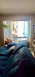 a bedroom with a blue bed with a large window at Apartamento com localização fantástica na praia de Balneário Camboriú in Balneário Camboriú