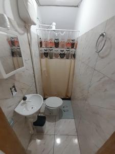 uma casa de banho com um WC, um chuveiro e um lavatório. em Hospedagem Suites Itaboraí em Itaboraí