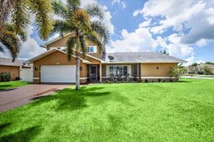 a house with a palm tree in the yard at Cape Coral Paradise 4 BD 12sleeps, W/heated pool in Cape Coral
