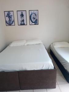 two beds in a bedroom with pictures on the wall at Encanto Guarapari in Guarapari