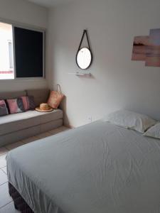 a white bedroom with a bed and a couch at Encanto Guarapari in Guarapari
