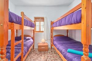 two bunk beds in a room with purple sheets at Casa Ian in Frigiliana