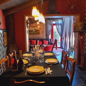 a dining room with a table with plates and wine glasses at A Pontiga I Casa Rural in Mezonzo