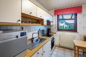 eine Küche mit weißen Schränken, einem Waschbecken und einem Fenster in der Unterkunft Haus am Twistesee in Wetterburg