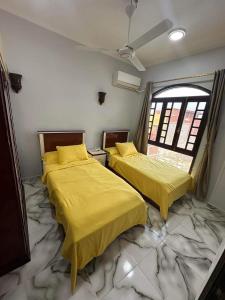 two beds with yellow covers in a room with a marble floor at Elwazan Hotel in Quseir