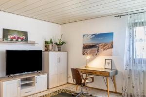 ein Wohnzimmer mit einem TV und einem Schreibtisch in der Unterkunft Haus am Twistesee in Wetterburg
