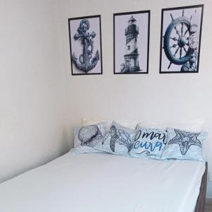 a white bed with four pictures on the wall at Encanto Guarapari in Guarapari