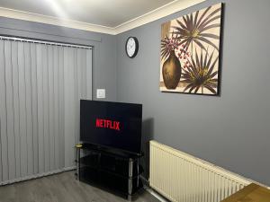 sala de estar con TV y reloj en la pared en Becky's Lodge - Strictly Single Adult Room Stays - No Double Adult Stays Allowed en Solihull