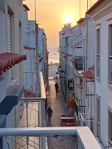 Gente caminando por una calle con sombrillas en la playa en Chalas bedroom, en Nazaré