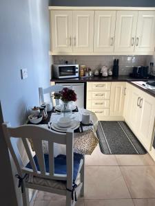 a kitchen with white cabinets and a table with flowers on it at Meelin cottage in Cork