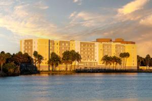 a large building with palm trees in front of the water at Homewood Suites Miami Airport/Blue Lagoon in Miami