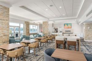 a dining room with tables and chairs and windows at Homewood Suites Miami Airport/Blue Lagoon in Miami