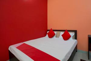 a red and white bed with red pillows on it at OYO Flagship Hotel R.M in Patna