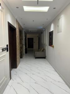 a hallway with white tile floors and a couch at قمم بارك النماص 8 Qimam Park Hotel in Al Namas