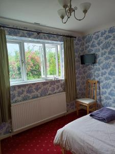 a bedroom with a bed and a chair and windows at Wansley Manor BnB Ltd in Birmingham