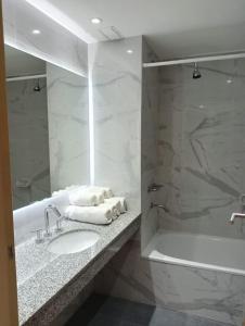 y baño con lavabo y bañera con toallas. en Hotel Neptuno en Mar del Plata