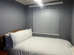 1 dormitorio con 1 cama blanca y ventana en Becky's Lodge - Strictly Single Adult Room Stays - No Double Adult Stays Allowed en Solihull