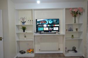 uma sala de estar com uma televisão de ecrã plano numa prateleira em Nice and Cosy Flat in London/Ilford/Barking, United Kingdom em Barking