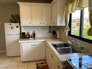 a kitchen with white cabinets and a sink and a refrigerator at 1 Bedroom Apartment, in Coconut Drive San Fernando in San Fernando