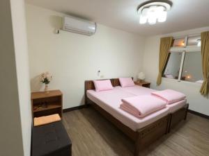 Schlafzimmer mit einem Bett mit rosa Kissen und einem Fenster in der Unterkunft 今友緣二館民宿 in Dongyin/