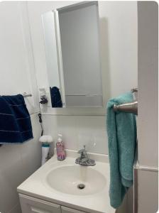a bathroom sink with a mirror and a blue towel at Home away from home in Laurelton
