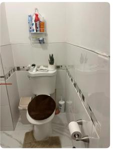 a white bathroom with a toilet with a brown seat at Home away from home in Laurelton