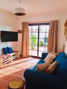 a living room with a blue couch and a large window at Casa La Pepita in Caleta De Fuste