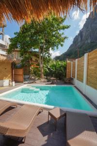 una piscina con 2 sillas y un árbol en Focus Rooms en El Nido