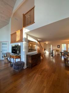 una gran sala de estar con suelo de madera y una escalera en KerryAnne - North Kawartha Lakehouse with Hot Tub, en woodview