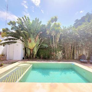 a swimming pool in front of a house with palm trees at CASA XTABENTUN in Mérida