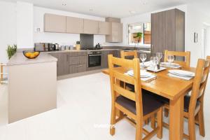 a kitchen with a wooden dining room table with chairs at Kiln Side by Truestays - 3 Bedroom House in Etruria