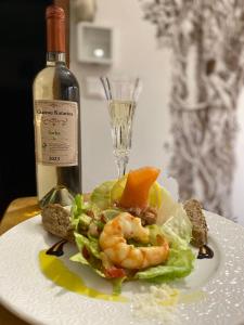 un plato de comida con camarones y una botella de vino en Chateau Katarína, en Vráble