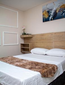 a bedroom with a large white bed with a wooden headboard at Hotel Horizon In in Santa Marta